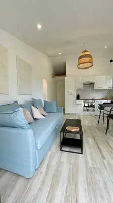 a living room with a blue couch and a table at Maisonnette chaleureuse a proximité du centre in Narbonne