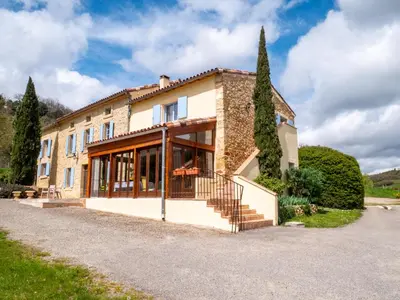 a large stone house with a staircase and trees at Gites et Roulottes au Domaine de la Trille in Sainte-Foi