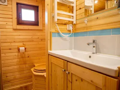a bathroom with a sink in a wooden cabin at Gites et Roulottes au Domaine de la Trille in Sainte-Foi