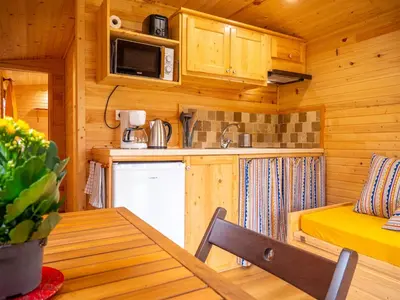 a kitchen and dining table in a wooden cabin at Gites et Roulottes au Domaine de la Trille in Sainte-Foi