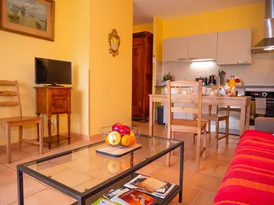 a living room with a table and a kitchen at Gites et Roulottes au Domaine de la Trille in Sainte-Foi