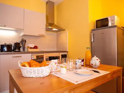 a kitchen with a table with a basket of bread at Gites et Roulottes au Domaine de la Trille in Sainte-Foi