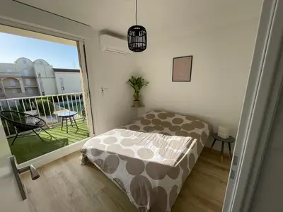 a bedroom with a bed and a large window at T3 Expo Sud-Est - Parking - Piscine - Clim - Wifi in Gruissan