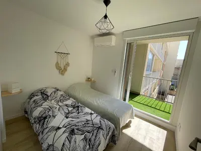 a bedroom with a bed and a large window at T3 Expo Sud-Est - Parking - Piscine - Clim - Wifi in Gruissan