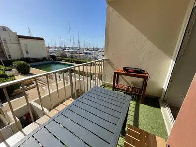 a balcony with a bench and a swimming pool at T3 Expo Sud-Est - Parking - Piscine - Clim - Wifi in Gruissan