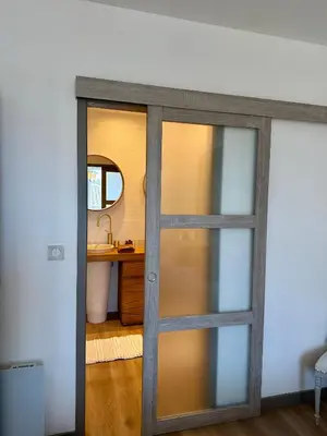 a sliding glass door in a bathroom with a sink at Coural' Chic in Narbonne
