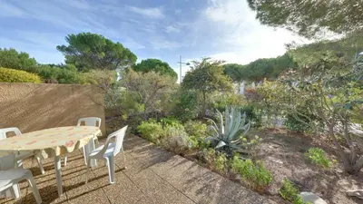 a patio with a table and chairs in a garden at Gruissan: Maisonnette T2 avec jardin in Gruissan