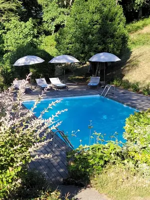 a swimming pool with two umbrellas and two chairs at Maison familiale de charme in Chalabre