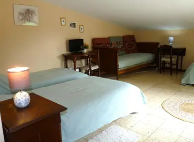 a bedroom with a bed and a living room at La Métairie de Lamourade, gîte nature in Saint-Ferriol
