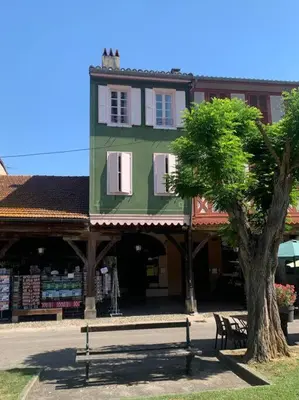 a green building with a bench next to a tree at Appartement mirepoix in Mirepoix