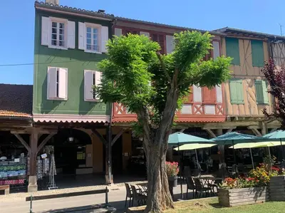 a tree in front of a building with tables and chairs at Appartement mirepoix in Mirepoix