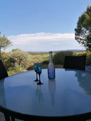 a table with a bottle and two glasses on it at Gîte Les Romarins Vue exceptionnelle ! in Saint-Jean-de-Minervois