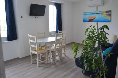 a living room with a table and chairs and a plant at Gîte Marin in Narbonne