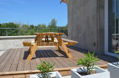 a wooden picnic table on a deck with plants at Gîte Marin in Narbonne