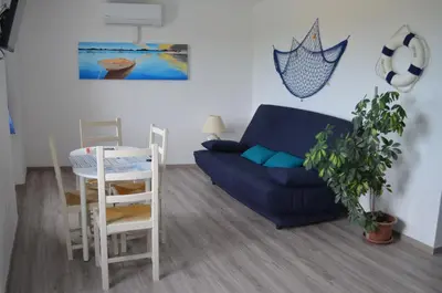 a living room with a blue couch and a table at Gîte Marin in Narbonne