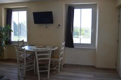 a dining room with a table and chairs and a television at Gîte Marin in Narbonne