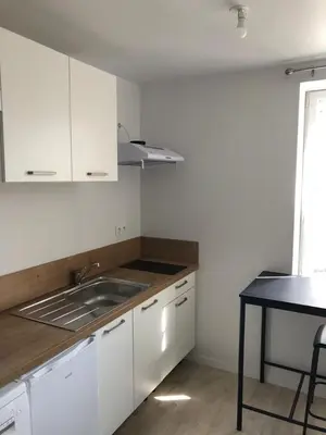 a kitchen with white cabinets and a sink and a table at Castres maisonnette proche du centre ville, parking et jardin in Castres