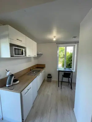 a kitchen with white cabinets and a table and a window at Castres maisonnette proche du centre ville, parking et jardin in Castres