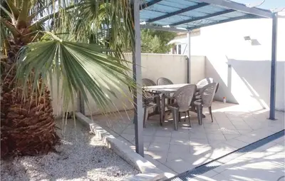 a patio with a table and chairs and a palm tree at Stunning Home In Ferrals Les Corbières in Ferrals-lès-Corbières