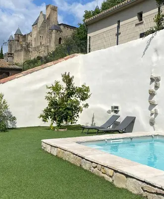 a swimming pool in a yard with a castle in the background at La Maison de La Tour Pinte in Carcassonne