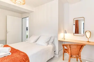 a white bedroom with a bed and a chair at Les Gîtes de Laure - L'Or Blanc, Appartement avec Vue sur le Chateau, Climatisation, Netflix, à 160 m de la Cité Médiévale in Carcassonne
