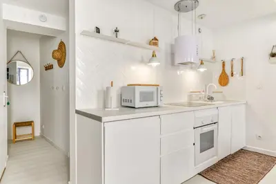 a kitchen with white cabinets and a microwave at Les Gîtes de Laure - L'Or Blanc, Appartement avec Vue sur le Chateau, Climatisation, Netflix, à 160 m de la Cité Médiévale in Carcassonne