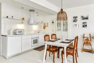 a white kitchen with a white table and chairs at Les Gîtes de Laure - L'Or Blanc, Appartement avec Vue sur le Chateau, Climatisation, Netflix, à 160 m de la Cité Médiévale in Carcassonne