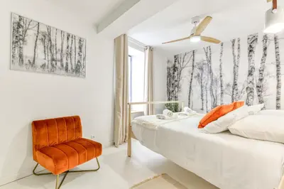 a bedroom with a bed and a chair at Les Gîtes de Laure - L'Or Blanc, Appartement avec Vue sur le Chateau, Climatisation, Netflix, à 160 m de la Cité Médiévale in Carcassonne