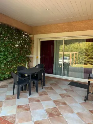 a patio with a black table and chairs on a porch at bienvenue chez nous in Badens