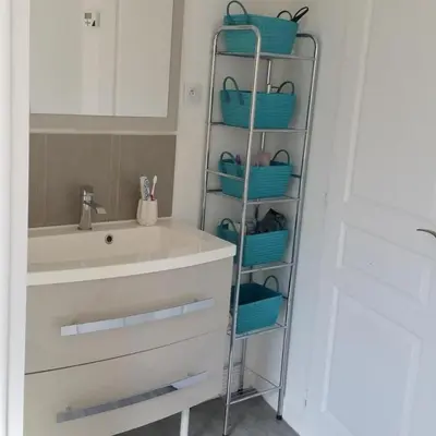 a bathroom with a shelf with baskets next to a sink at Horizon Caramany : un havre de douceur, vue lac ! in Caramany