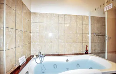 a bath tub in a bathroom with a tiled wall at 2 Bedroom Gorgeous Home In Carcassonne in Carcassonne