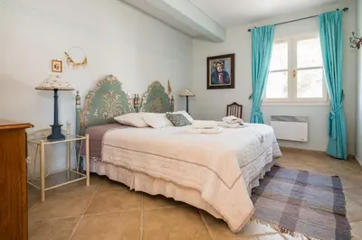 a bedroom with a large bed with blue curtains at La closerie des iris in Castelnau-dʼAude