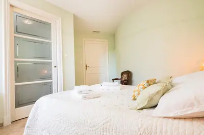 a white bed in a room with a window at La closerie des iris in Castelnau-dʼAude