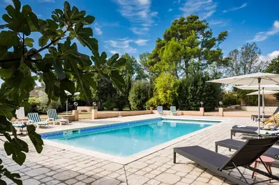 a swimming pool with lounge chairs and an umbrella at La closerie des iris in Castelnau-dʼAude