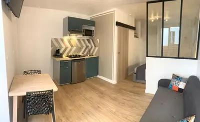 a living room with a couch and a table and a kitchen at Appartement avec terrasse au cœur de Carcassonne - Serviettes Draps Ménage inclus in Carcassonne