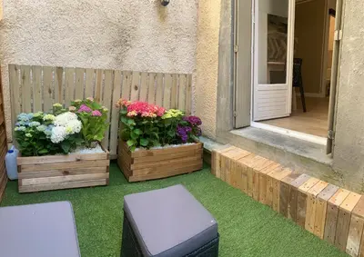 a patio with two wooden boxes with flowers on it at Appartement avec terrasse au cœur de Carcassonne - Serviettes Draps Ménage inclus in Carcassonne