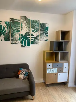 a living room with a couch and palm leaves painting at Appartement avec terrasse au cœur de Carcassonne - Serviettes Draps Ménage inclus in Carcassonne