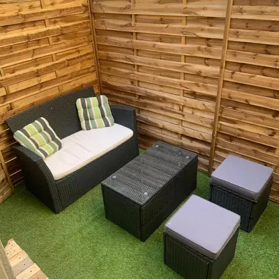 a patio with a wicker chair and two ottomans and a table at Appartement avec terrasse au cœur de Carcassonne - Serviettes Draps Ménage inclus in Carcassonne