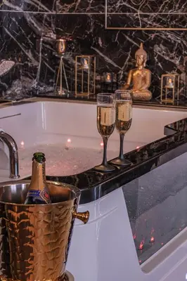 a bath tub with two glasses of champagne and a champagne bottle at Magnifique loft / spa en face de la cathédrale ! in Narbonne
