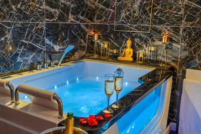 a bath tub with two wine glasses and a sink at Magnifique loft / spa en face de la cathédrale ! in Narbonne
