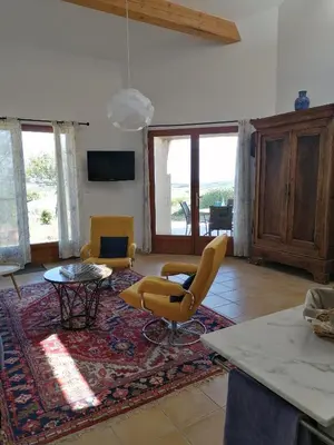 a living room with yellow chairs and a table at Les romarins in Saint-Jean-de-Minervois