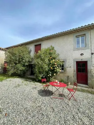 a red table and chairs in front of a house at Le cazal in Sainte-Eulalie