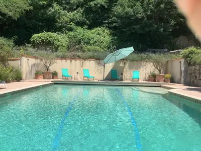 a swimming pool with blue chairs and an umbrella at The Gatehouse in Castres