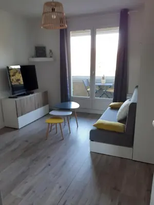a living room with a bed and a tv and a table at Studio Balcon Proche Hypercentre de Narbonne in Narbonne