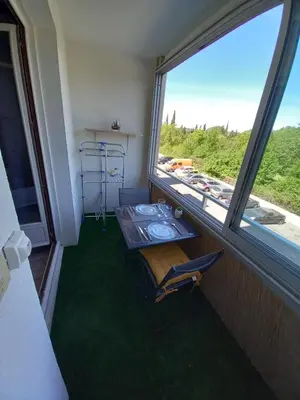 a dining room with a table and a large window at Studio Balcon Proche Hypercentre de Narbonne in Narbonne