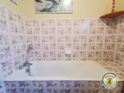 a bath tub in a bathroom with pink flowers at Le janabel in Prades-sur-Vernazobre