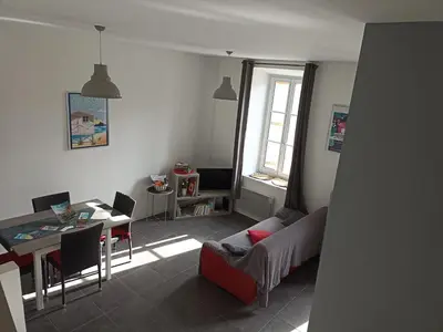 a living room with a table and a couch and a dining room at Jolie Maison au centre du village in Gruissan