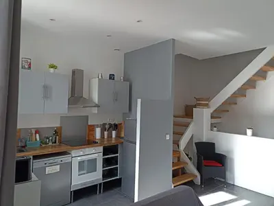a kitchen with white cabinets and a staircase at Jolie Maison au centre du village in Gruissan