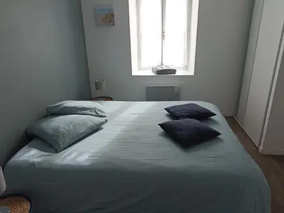 a large bed with three pillows on it in a bedroom at Jolie Maison au centre du village in Gruissan