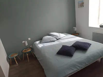 a bedroom with a bed with two tables and two pillows at Jolie Maison au centre du village in Gruissan